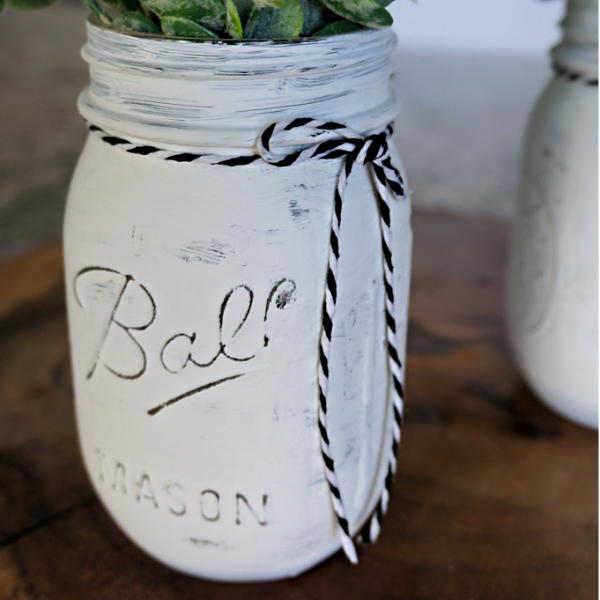 DIY Rustic Mason Jar Decor - DIY Farmhouse Decor Chalk painted mason jars can be one of the most useful rustic home decor items. Create a mason jar farmhouse centerpiece in minutes! Switch out the greenery to match any season, holiday, or color scheme.